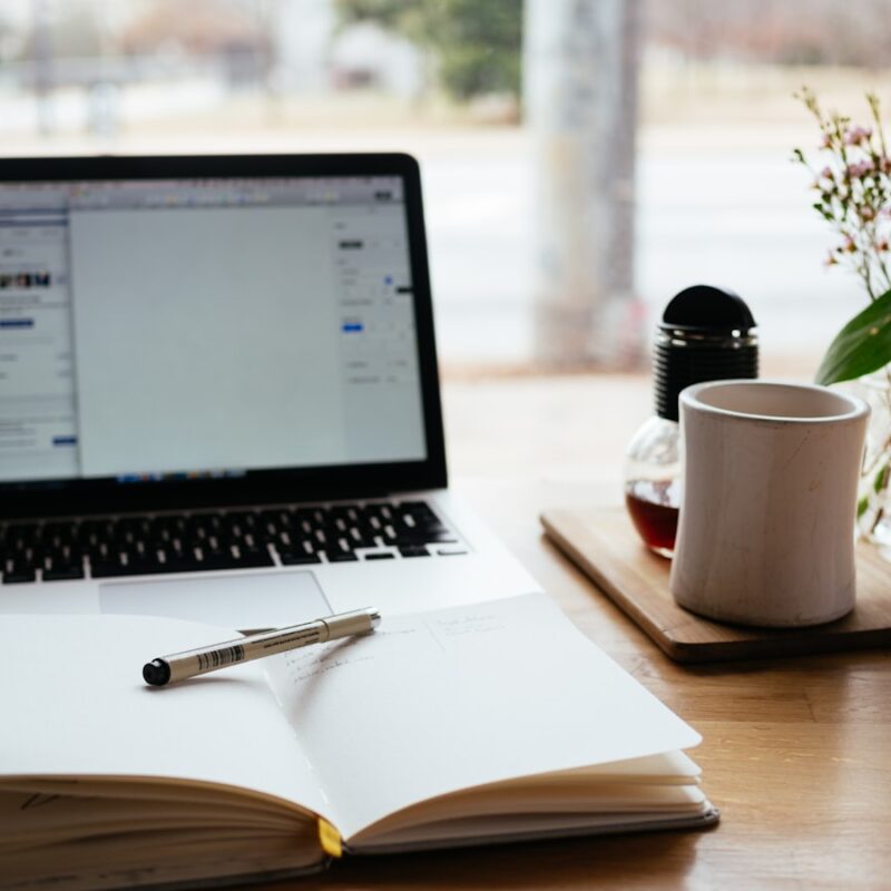 Open laptop and notebook on a desk with coffee, thoughtful workspace