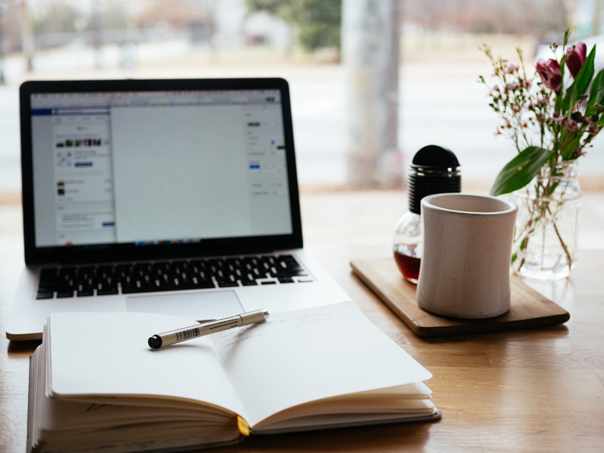 Open laptop and notebook on a desk with coffee, thoughtful workspace